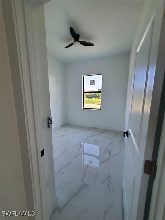 3117 35th St SW, Lehigh Acres, FL 33976 - empty room featuring marble look tiles and a ceiling fan