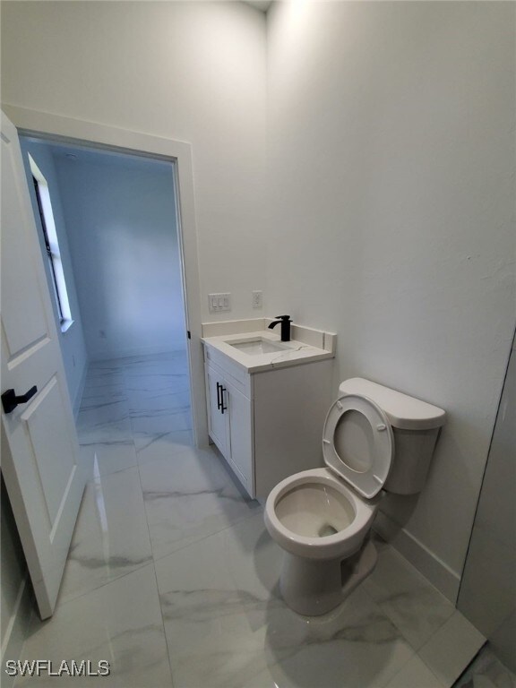 3117 35th St SW, Lehigh Acres, FL 33976 - bathroom with marble look tile flooring, toilet, vanity, and baseboards