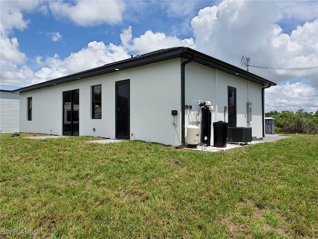 3117 35th St SW, Lehigh Acres, FL 33976 - back of property featuring stucco siding, a yard, and central AC