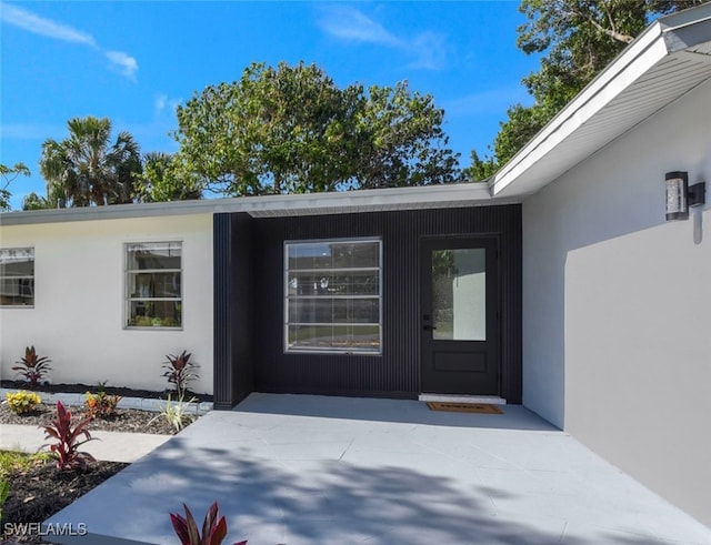property entrance with stucco siding and a patio area