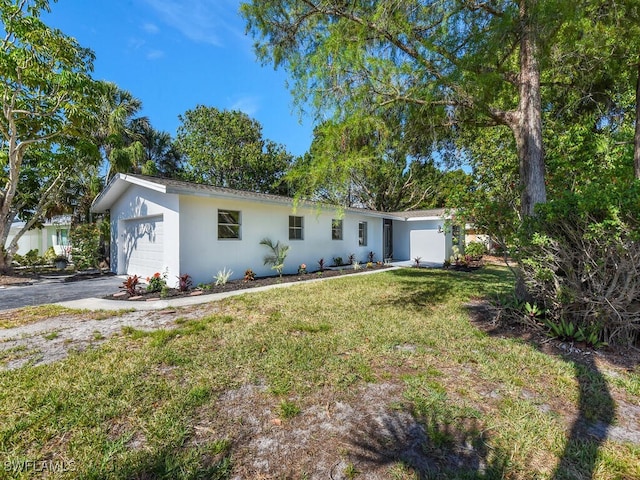 ranch-style house with a garage, stucco siding, aphalt driveway, and a front yard