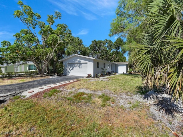 view of front facade with an attached garage, aphalt driveway, stucco siding, and a front yard