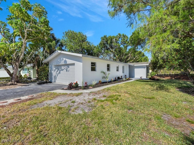 single story home featuring aphalt driveway, stucco siding, and a front yard
