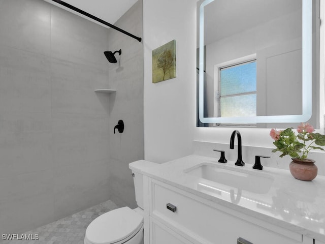 bathroom featuring vanity, toilet, and tiled shower