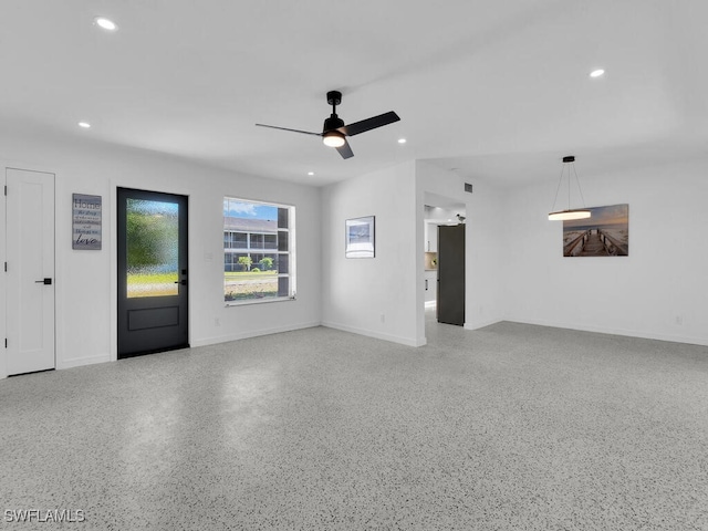 unfurnished living room with a ceiling fan, baseboards, recessed lighting, and speckled floor