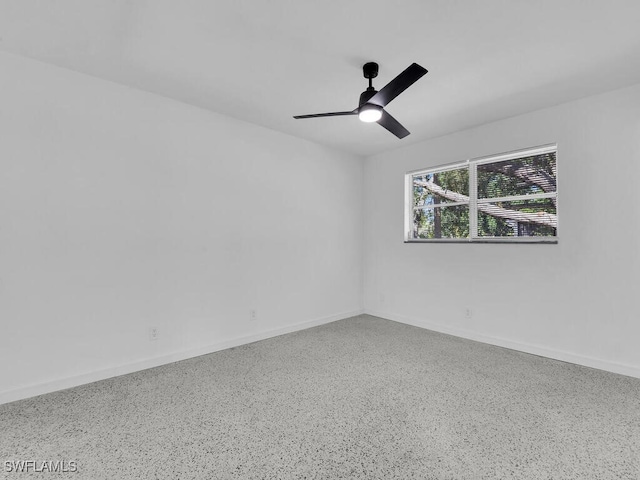spare room featuring a ceiling fan, baseboards, and speckled floor