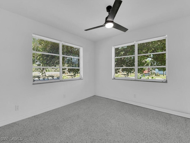 spare room featuring a ceiling fan, baseboards, and speckled floor