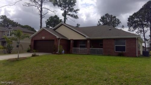 3905 16th St W, Lehigh Acres, FL 33971 - single story home featuring driveway, a porch, a front lawn, and an attached garage