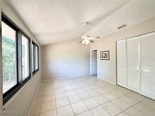 unfurnished bedroom featuring light tile patterned flooring, visible vents, lofted ceiling, and a closet
