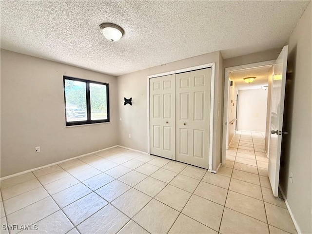 unfurnished bedroom with light tile patterned floors, baseboards, a closet, and a textured ceiling