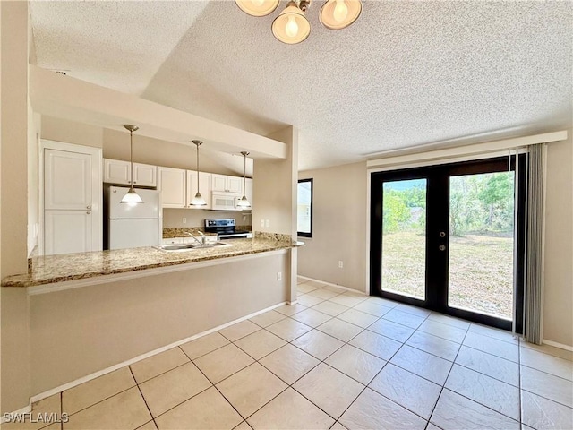 kitchen featuring a sink, a peninsula, white appliances, and light stone countertops