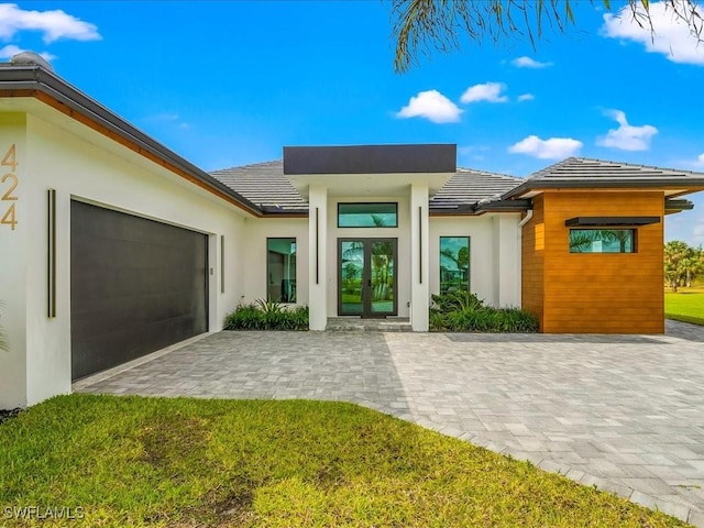 entrance to property featuring an attached garage, stucco siding, decorative driveway, and a tile roof