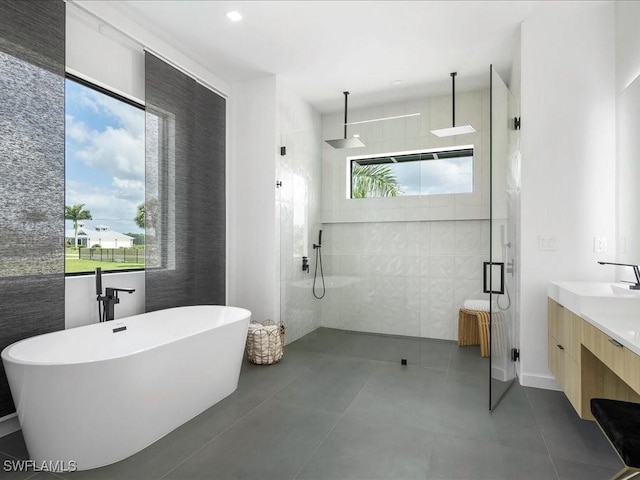 bathroom featuring vanity, a freestanding tub, a stall shower, and tile walls