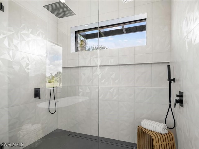 bathroom with a walk in shower, tile walls, and tile patterned flooring