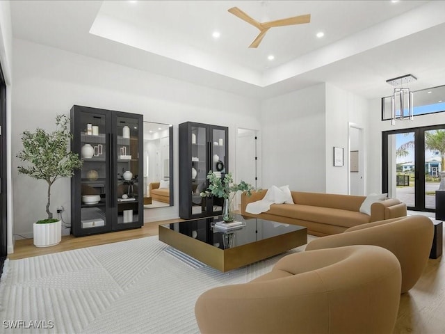 living room featuring a high ceiling, a tray ceiling, and wood finished floors