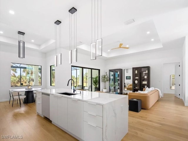 kitchen with modern cabinets, white cabinetry, a tray ceiling, a sink, and dishwasher