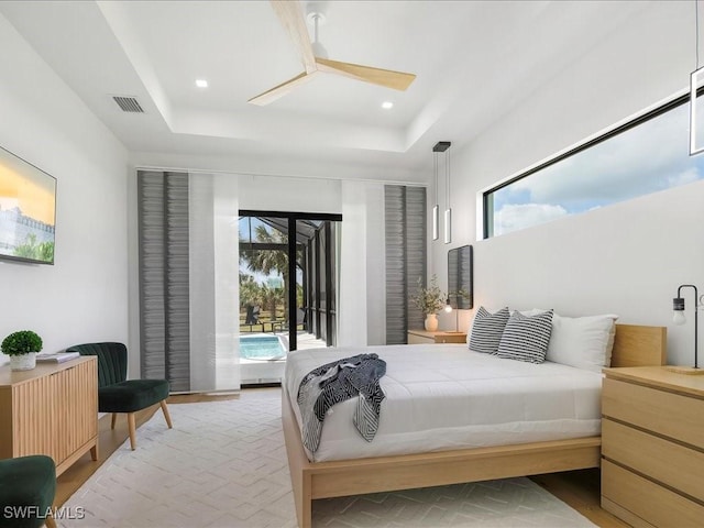 bedroom featuring access to outside, a raised ceiling, a ceiling fan, wood finished floors, and visible vents