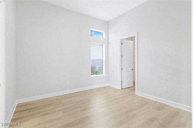 spare room featuring baseboards and light wood-style floors