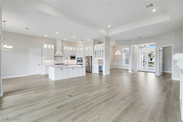unfurnished living room featuring light wood-style flooring, an inviting chandelier, and plenty of natural light