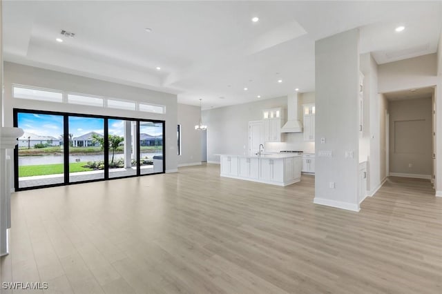 unfurnished living room featuring a sink, light wood-type flooring, visible vents, baseboards, and recessed lighting