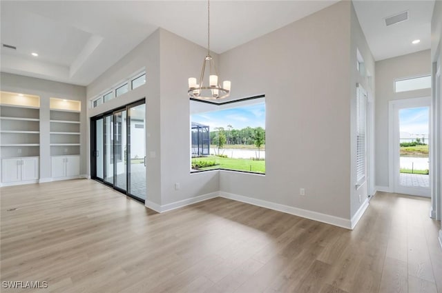 unfurnished dining area featuring light wood finished floors, plenty of natural light, and built in shelves