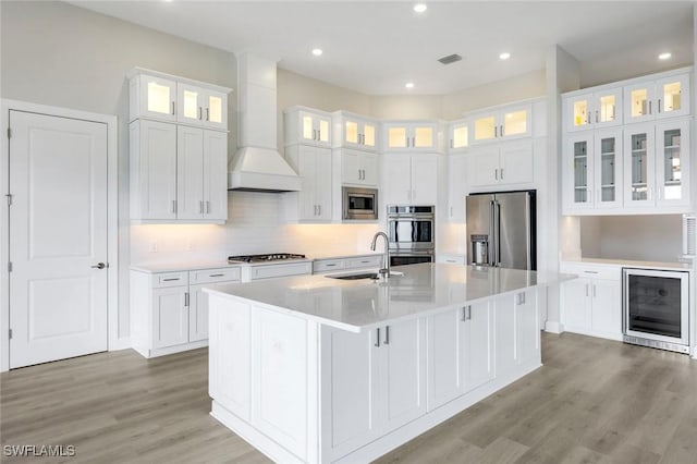kitchen featuring beverage cooler, visible vents, a sink, a kitchen island with sink, and appliances with stainless steel finishes