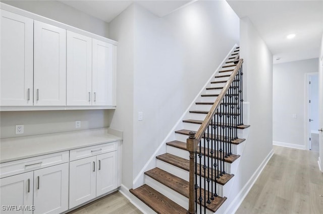 stairway featuring wood finished floors, baseboards, and recessed lighting
