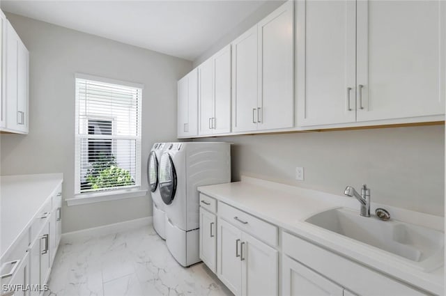 washroom with baseboards, marble finish floor, a sink, separate washer and dryer, and cabinet space