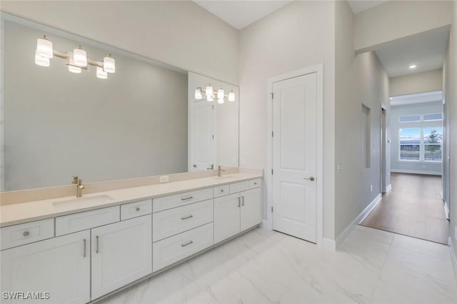 bathroom with a sink, double vanity, baseboards, and marble finish floor