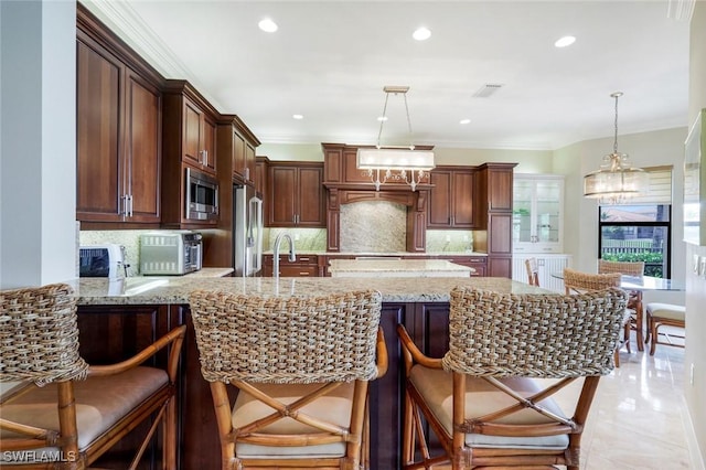 kitchen with stainless steel appliances, backsplash, a peninsula, light stone counters, and pendant lighting