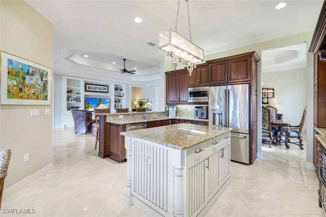 kitchen with appliances with stainless steel finishes, a tray ceiling, a sink, ceiling fan, and a peninsula