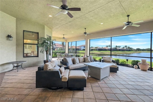 view of patio featuring a ceiling fan, an outdoor living space, and a water view