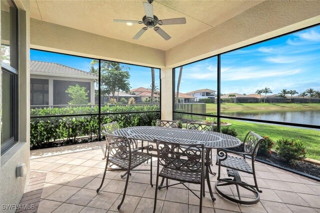 sunroom / solarium featuring a water view, a ceiling fan, outdoor dining area, and a residential view