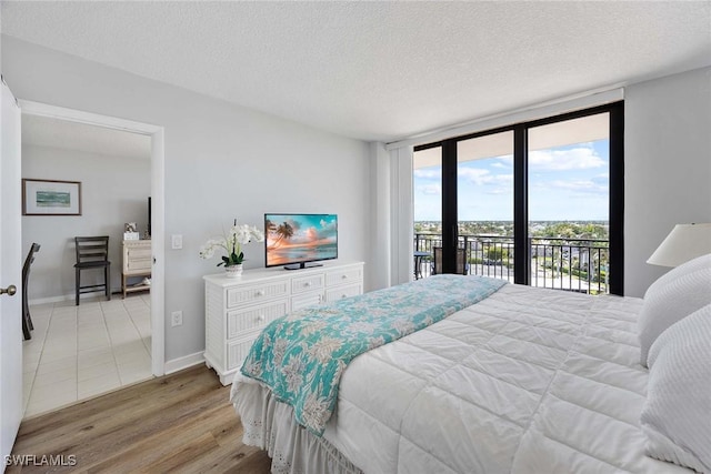 180 Seaview Ct Unit 814, Marco Island, FL 34145 - bedroom featuring expansive windows, a textured ceiling, light wood-type flooring, baseboards, and access to outside