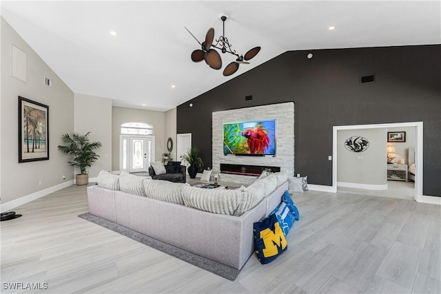1255 Eider Ct, Punta Gorda, FL 33950 - living area featuring light wood-style floors, baseboards, a ceiling fan, a glass covered fireplace, and high vaulted ceiling