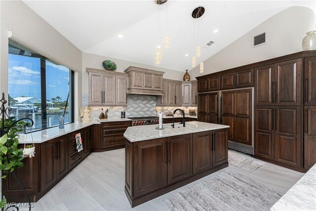 1255 Eider Ct, Punta Gorda, FL 33950 - kitchen featuring lofted ceiling, paneled fridge, decorative backsplash, custom exhaust hood, and a kitchen island with sink