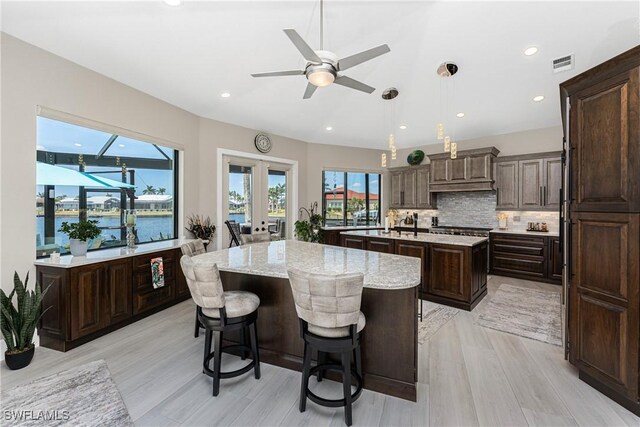 1255 Eider Ct, Punta Gorda, FL 33950 - kitchen featuring a kitchen island with sink, dark brown cabinetry, tasteful backsplash, ceiling fan, and decorative light fixtures