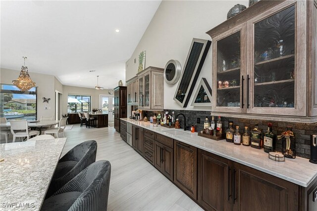 1255 Eider Ct, Punta Gorda, FL 33950 - bar featuring a sink, backsplash, light wood-type flooring, a towering ceiling, and decorative light fixtures