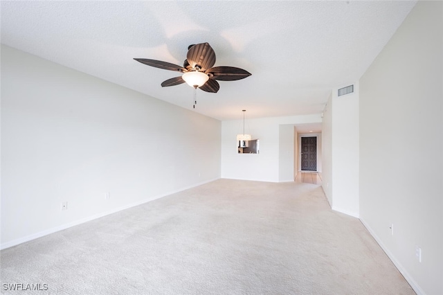 unfurnished room featuring light colored carpet, a ceiling fan, and baseboards
