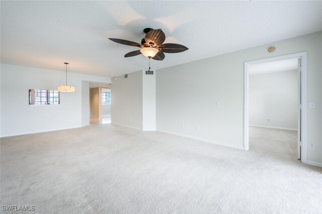 empty room featuring light colored carpet, a ceiling fan, and baseboards