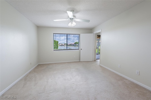 empty room with light carpet, a ceiling fan, a textured ceiling, and baseboards