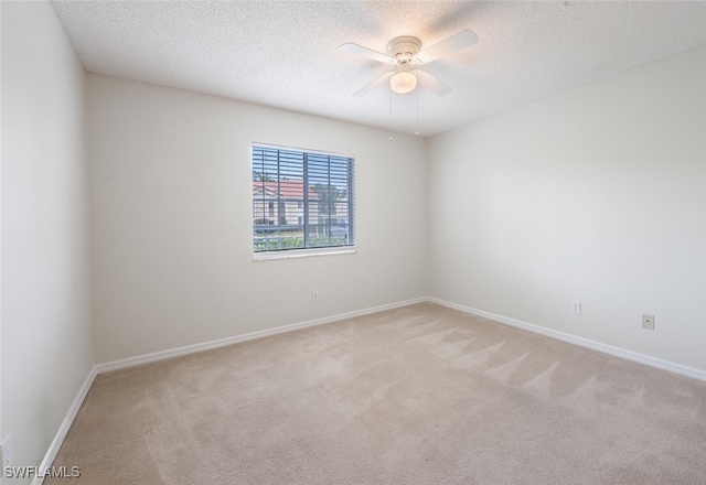 empty room with light colored carpet, a textured ceiling, ceiling fan, and baseboards