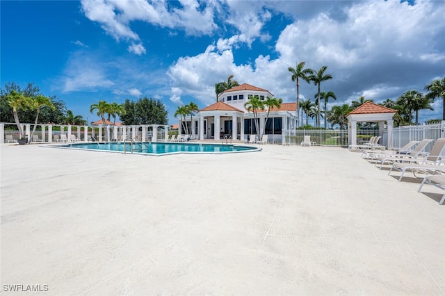 community pool with fence, a gazebo, and a patio