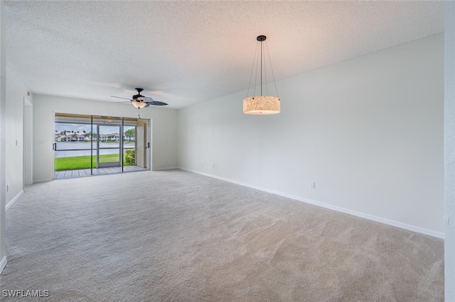 unfurnished room with carpet flooring, a ceiling fan, baseboards, and a textured ceiling
