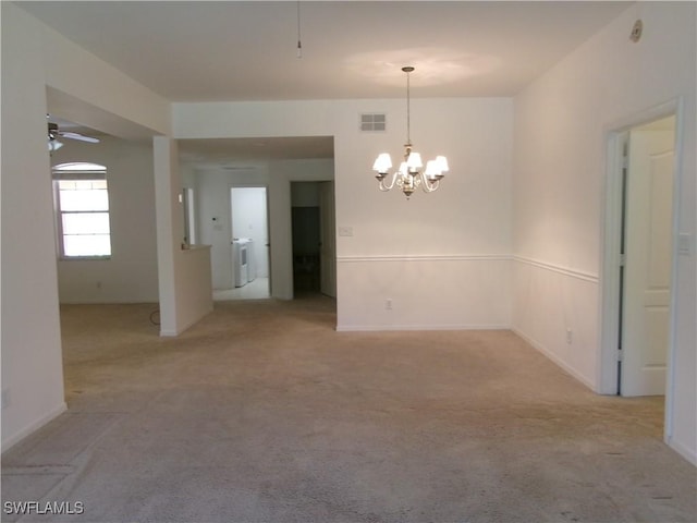 spare room featuring washer / dryer, light colored carpet, ceiling fan with notable chandelier, and visible vents