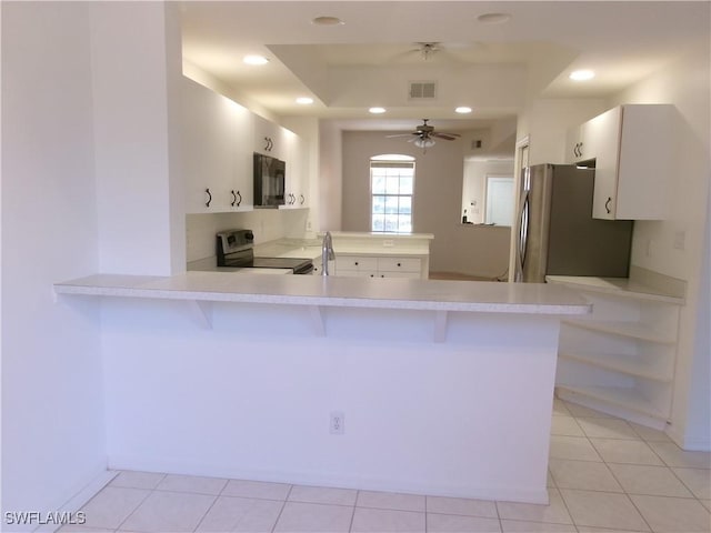 kitchen featuring visible vents, a peninsula, a kitchen breakfast bar, light countertops, and appliances with stainless steel finishes