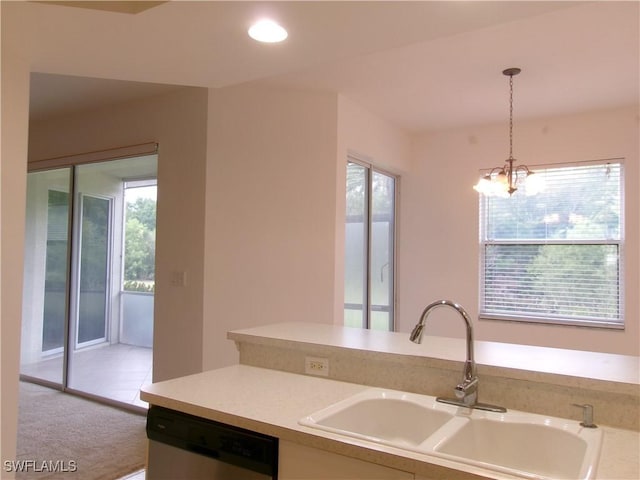 kitchen featuring stainless steel dishwasher, a sink, pendant lighting, light countertops, and a chandelier