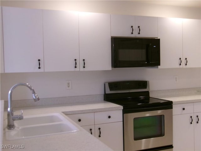 kitchen featuring black microwave, stainless steel range with electric stovetop, a sink, and light countertops