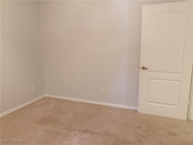 spare room with light colored carpet and baseboards