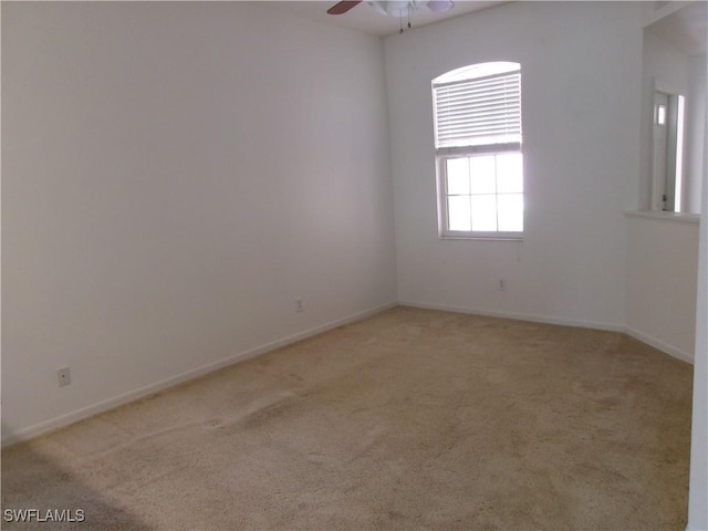 empty room featuring light carpet, a ceiling fan, and baseboards